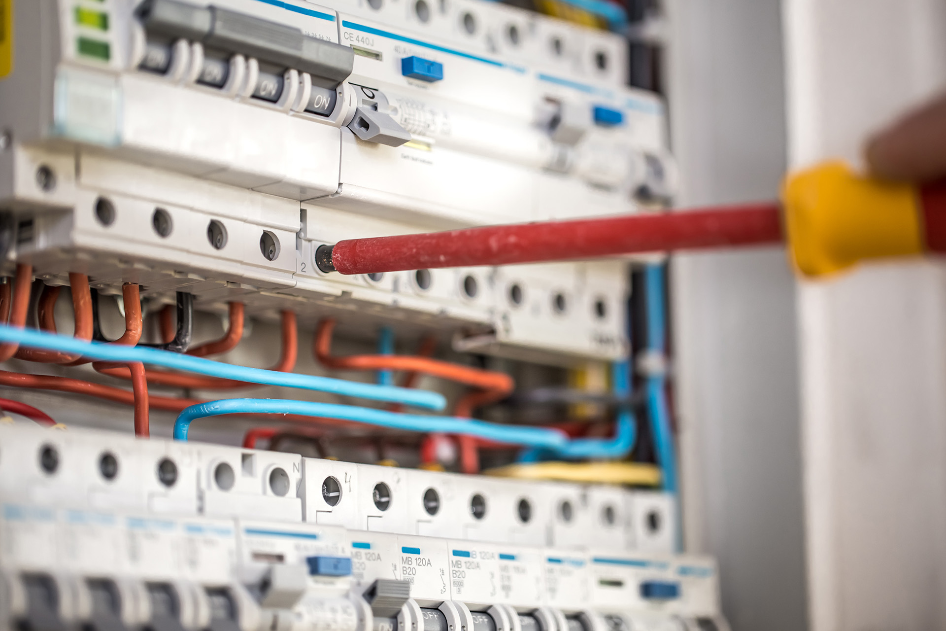 Man, an electrical technician working in a switchboard with fuses. Installation and connection of electrical equipment. Close up.